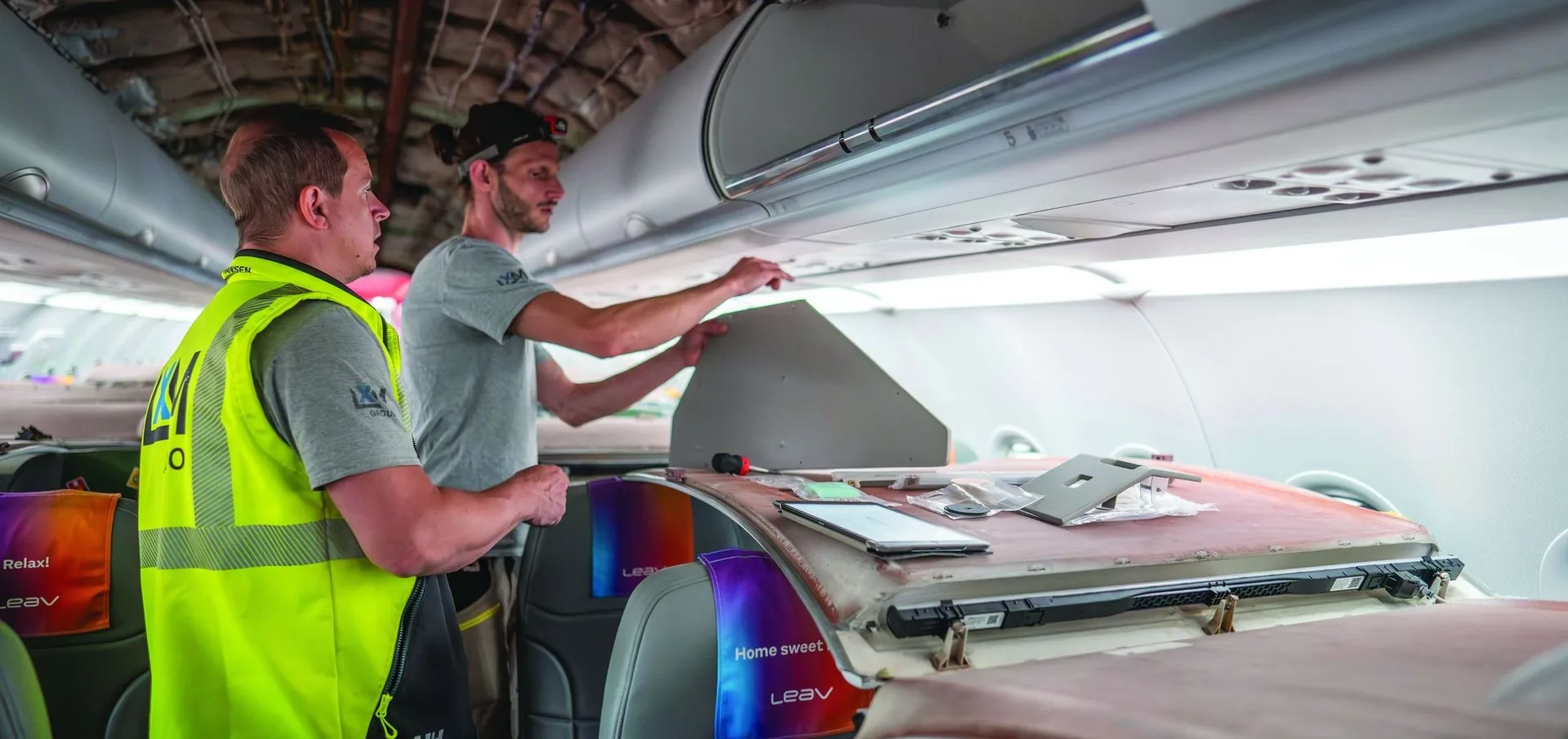 Technicians working at an open overhead bin during a cabin installation