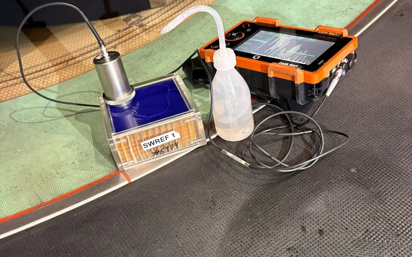 Ultrasonic flaw detector and reference block on a composite panel during inspection